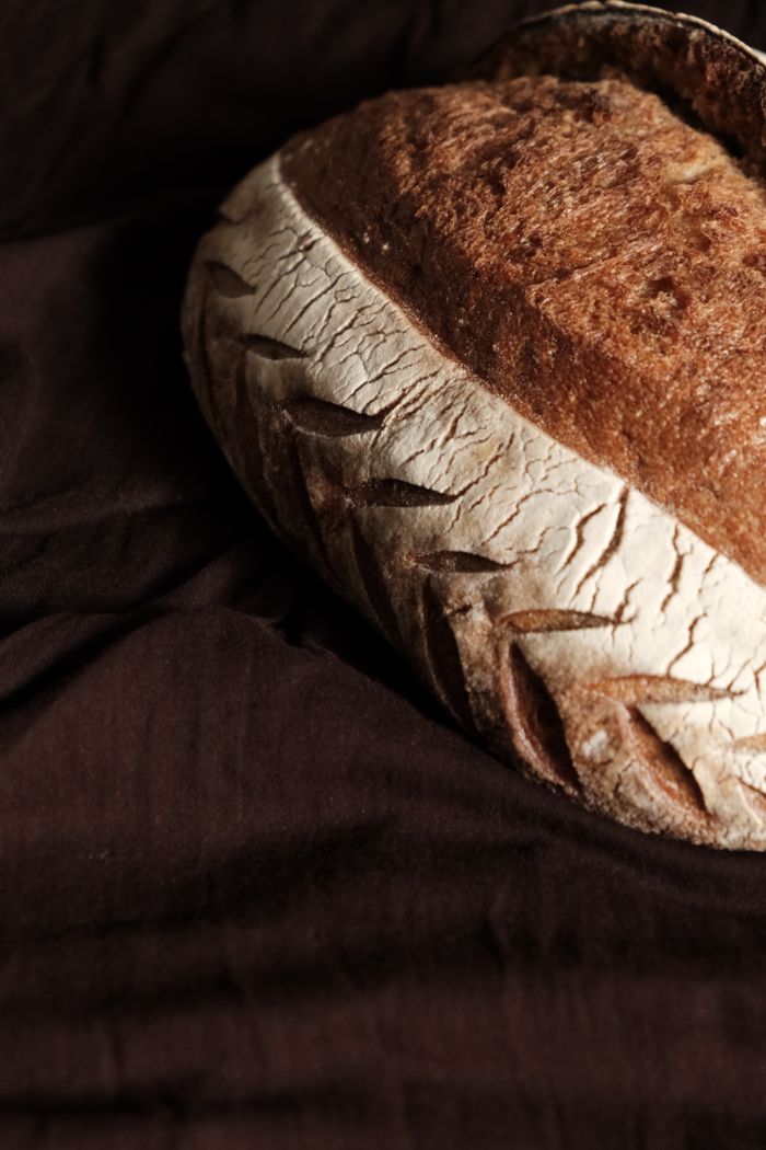 A close-up of artisanal bread with a crusty texture on a dark rustic background.